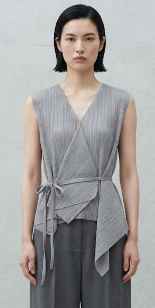 Grey Pleated Wrap Top with Tie Belt (Category: Sleeveless) located in Donsol. Submitted by saksthriftavenuebyluckymaria8 (Listing ID 1460840439, Image 1). Description: - Sleeveless grey top - Flattering V-neckline - Chic wrap-around design - Includes matching waist tie belt - Unique pleat fabric detail - Versatile: pairs well with trousers or Skirts length 22in assymetrical.