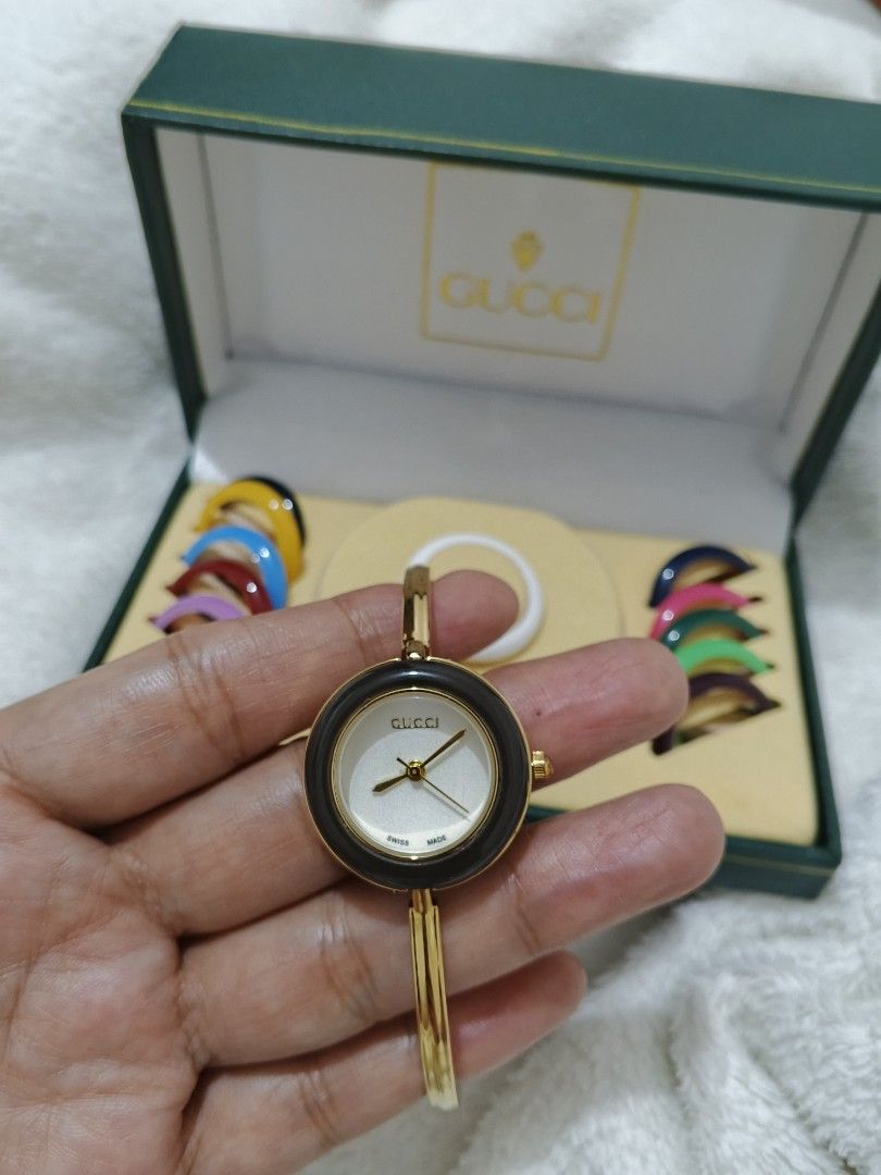 Gucci Watch with Interchangeable Bezels (Category: Women's Watches) located in Manila. Submitted by ghie_0116 (Listing ID 1460802703, Image 2). Description: Gucci watch with a gold-tone bangle. Comes with multiple interchangeable bezel colors: yellow, blue, red, purple, green, and brown. The watch face is round with a white dial. Original box included. Great for customizing your look..