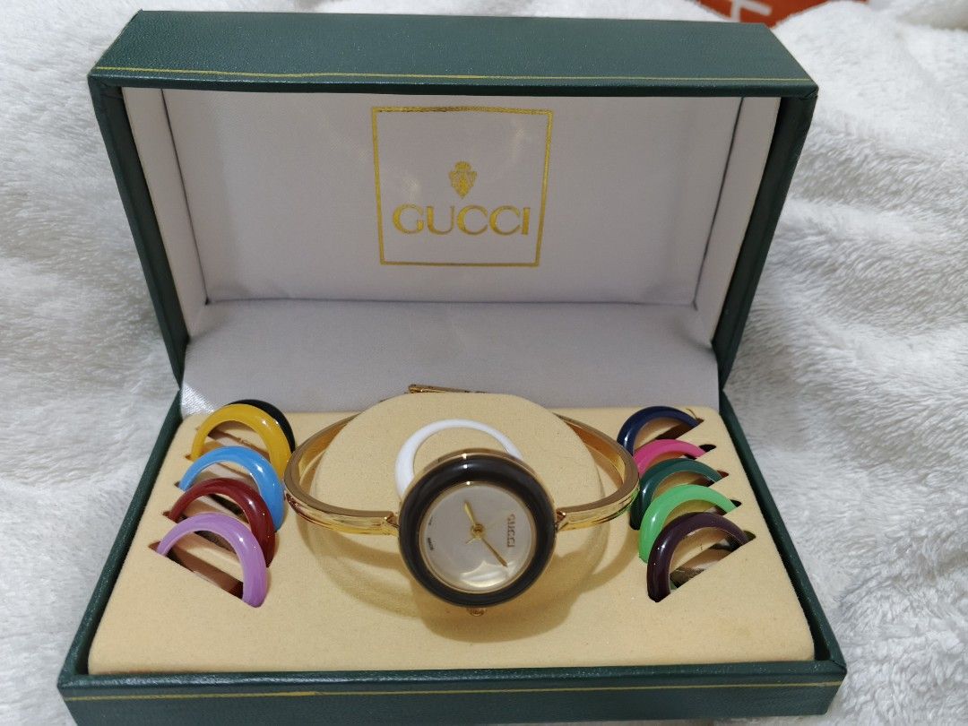 Gucci Watch with Interchangeable Bezels (Category: Women's Watches) located in Manila. Submitted by ghie_0116 (Listing ID 1460802703, Image 1). Description: Gucci watch with a gold-tone bangle. Comes with multiple interchangeable bezel colors: yellow, blue, red, purple, green, and brown. The watch face is round with a white dial. Original box included. Great for customizing your look..