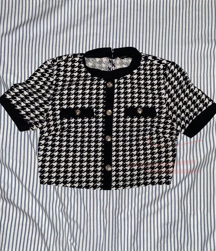 Houndstooth Button-Up Short Sleeve Top (Category: Blouses) located in Manila. Submitted by _dayanughhhh (Listing ID 1460871370, Image 1). Description: - Classic black and white houndstooth pattern - Short sleeves with black trim - Button-up front with silver buttons - Two decorative chest pockets - Versatile for dressing up or down.