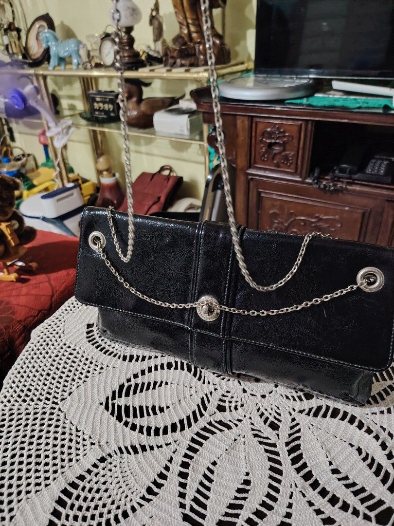 INTERPLANET Black Patent Leather Chain Clutch Bag (Category: Clutches) located in Luisiana. Submitted by sahayamay77 (Listing ID 1460766230, Image 3). Description: - Sleek black patent leather clutch bag - Elegant silver chain strap - Interior lining features INTERPLANET logo - Secure magnetic snap closure - Ideal for evening events and special occasions - Approximate dimensions: 12 inches long, 4 inches tall (folded).
