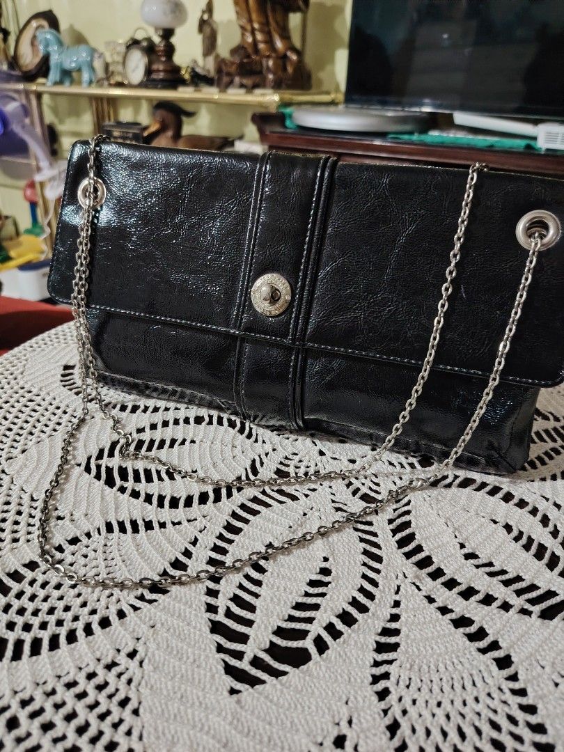 INTERPLANET Black Patent Leather Chain Clutch Bag (Category: Clutches) located in Luisiana. Submitted by sahayamay77 (Listing ID 1460766230, Image 1). Description: - Sleek black patent leather clutch bag - Elegant silver chain strap - Interior lining features INTERPLANET logo - Secure magnetic snap closure - Ideal for evening events and special occasions - Approximate dimensions: 12 inches long, 4 inches tall (folded).