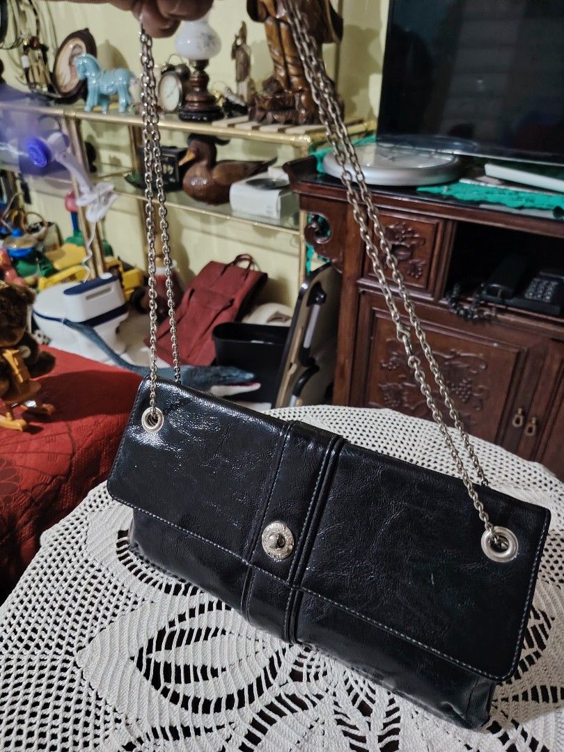 INTERPLANET Black Patent Leather Chain Clutch Bag (Category: Clutches) located in Luisiana. Submitted by sahayamay77 (Listing ID 1460766230, Image 2). Description: - Sleek black patent leather clutch bag - Elegant silver chain strap - Interior lining features INTERPLANET logo - Secure magnetic snap closure - Ideal for evening events and special occasions - Approximate dimensions: 12 inches long, 4 inches tall (folded).