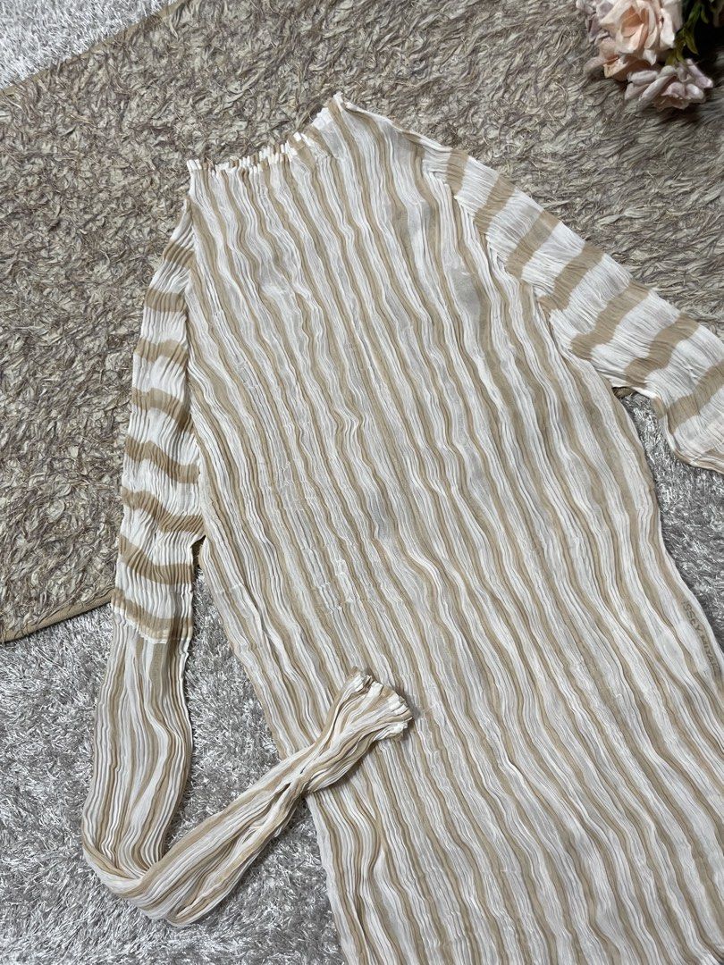 Issey Miyake Top (Category: Luxury Apparel) located in Manila. Submitted by rutchemari68583 (Listing ID 1460768628, Image 2). Description: - Authentic Issey Miyake top - Beige and white striped pattern - Signature Issey Miyake pleats - High neckline and long sleeves - Unique, textured fabric - Versatile for layering or standalone wear - Classic designer piece.