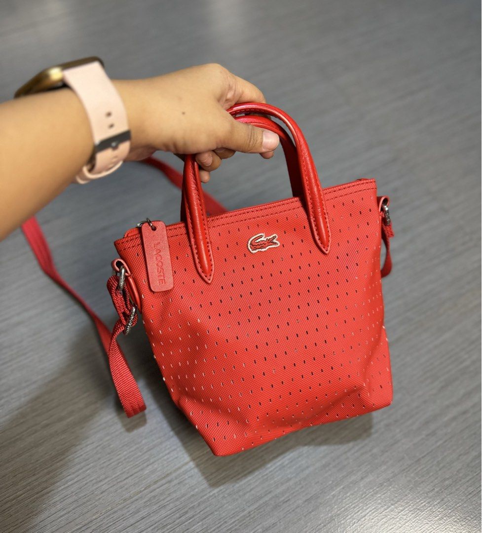 Lacoste Red Perforated Tote Bag with Strap (Category: Shoulder Bags) located in Manila. Submitted by mzcollection_349 (Listing ID 1460722456, Image 3). Description: - Authentic Red Lacoste tote bag - Stylish perforated design all over - Comfortable top handles - Includes a detachable crossbody strap for versatile wear - Secure zipper closure - Small tag detail and interior tag for authenticity - Ideal for everyday use.