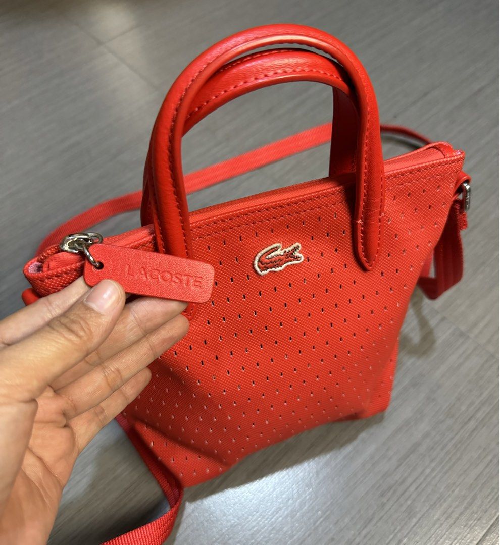Lacoste Red Perforated Tote Bag with Strap (Category: Shoulder Bags) located in Manila. Submitted by mzcollection_349 (Listing ID 1460722456, Image 2). Description: - Authentic Red Lacoste tote bag - Stylish perforated design all over - Comfortable top handles - Includes a detachable crossbody strap for versatile wear - Secure zipper closure - Small tag detail and interior tag for authenticity - Ideal for everyday use.