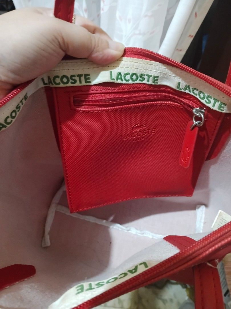Lacoste Red Tote Bag (Category: Tote Bags) located in Cavite. Submitted by ms.de.clutter (Listing ID 1460790761, Image 2). Description: - Red Lacoste tote bag - Signature crocodile logo on the front - Interior zippered pocket - Small interior pouch - Handles show some wear - Ideal for everyday use.