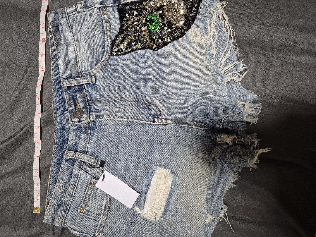 Light Wash Denim Shorts with Sequin Cat Patch (Category: Shorts) located in Santo Tomas. Submitted by bellaswann18 (Listing ID 1460816477, Image 2). Description: - Cute light wash denim shorts - Distressed look with rips and frayed hem - Adorable sequin cat patch with green eyes on the right side - Perfect for a casual and edgy outfit - Measurements are available in the photos - Ready for a new owner!.