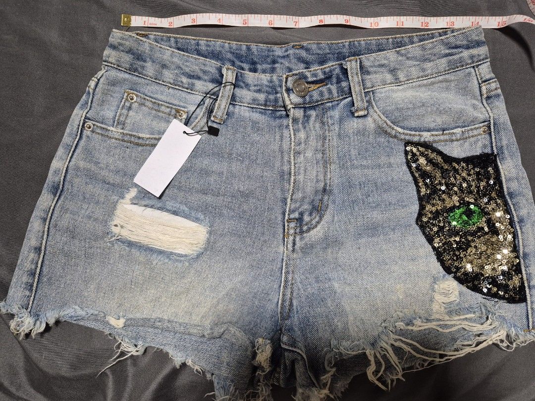 Light Wash Denim Shorts with Sequin Cat Patch (Category: Shorts) located in Santo Tomas. Submitted by bellaswann18 (Listing ID 1460816477, Image 1). Description: - Cute light wash denim shorts - Distressed look with rips and frayed hem - Adorable sequin cat patch with green eyes on the right side - Perfect for a casual and edgy outfit - Measurements are available in the photos - Ready for a new owner!.