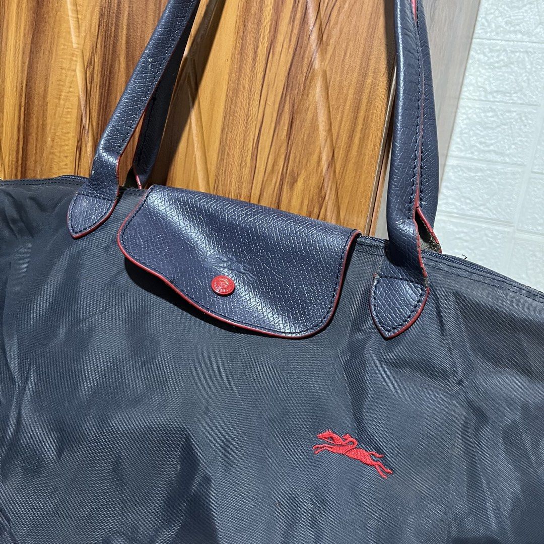 Longchamp Le Pliage Tote Bag Dark Grey (Category: Luxury Bags & Wallets) located in Carmen. Submitted by rr_thrifts (Listing ID 1460716288, Image 2). Description: - Classic Longchamp tote bag - Accents: Red details on flap and zipper pull - Features: Spacious interior, foldable for easy storage - Ideal for: Travel and everyday use.