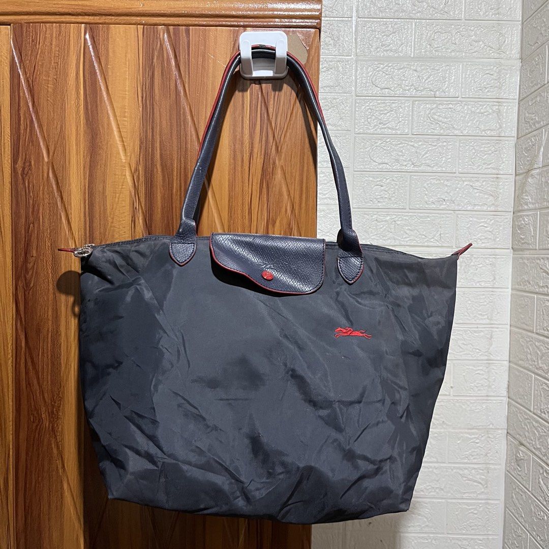 Longchamp Le Pliage Tote Bag Dark Grey (Category: Luxury Bags & Wallets) located in Carmen. Submitted by rr_thrifts (Listing ID 1460716288, Image 1). Description: - Classic Longchamp tote bag - Accents: Red details on flap and zipper pull - Features: Spacious interior, foldable for easy storage - Ideal for: Travel and everyday use.