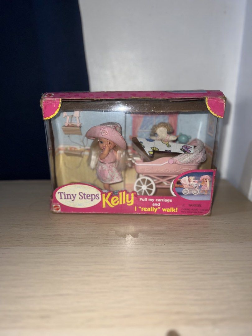 Mattel Kelly Tiny Steps Doll with Walking Carriage (Category: Kids Toys) located in Manila. Submitted by asa68984 (Listing ID 1460876076, Image 1). Description: - Mattel Kelly Tiny Steps doll set - Includes doll and pink carriage - Carriage is designed to 'walk' when pulled - Box shows some wear - Great for collectors or play.