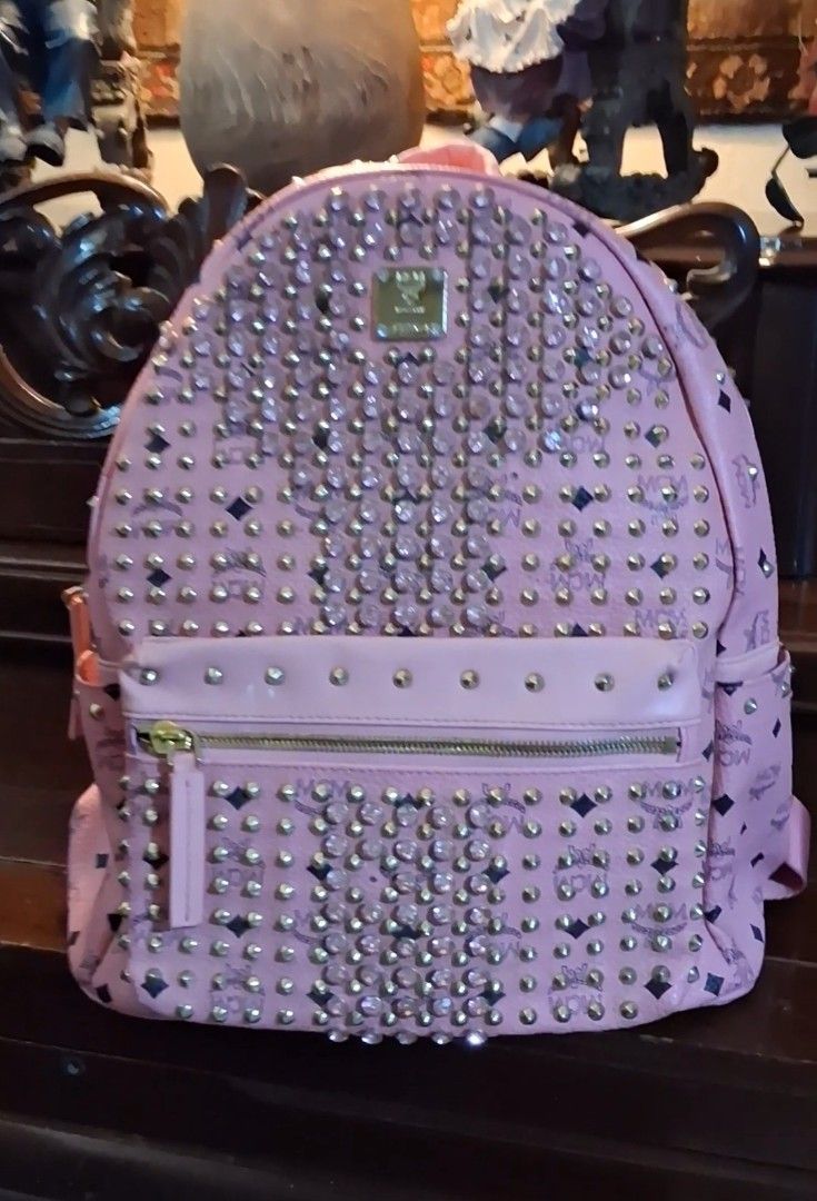 MCM Pink Studded Backpack with Crystals (Category: Backpacks) located in Taguig. Submitted by divine_kitty (Listing ID 1460917381, Image 1). Description: -Authemtic MCM STARCK MCM BACKPACK -SPECIAL EDITION Made in Korea - Eye-catching pink MCM backpack - Adorned with shimmering gold studs and clear crystals - Features the classic MCM logo pattern throughout - Secure zipper closure with a convenient front pocket - Adjustable straps for a comfortab