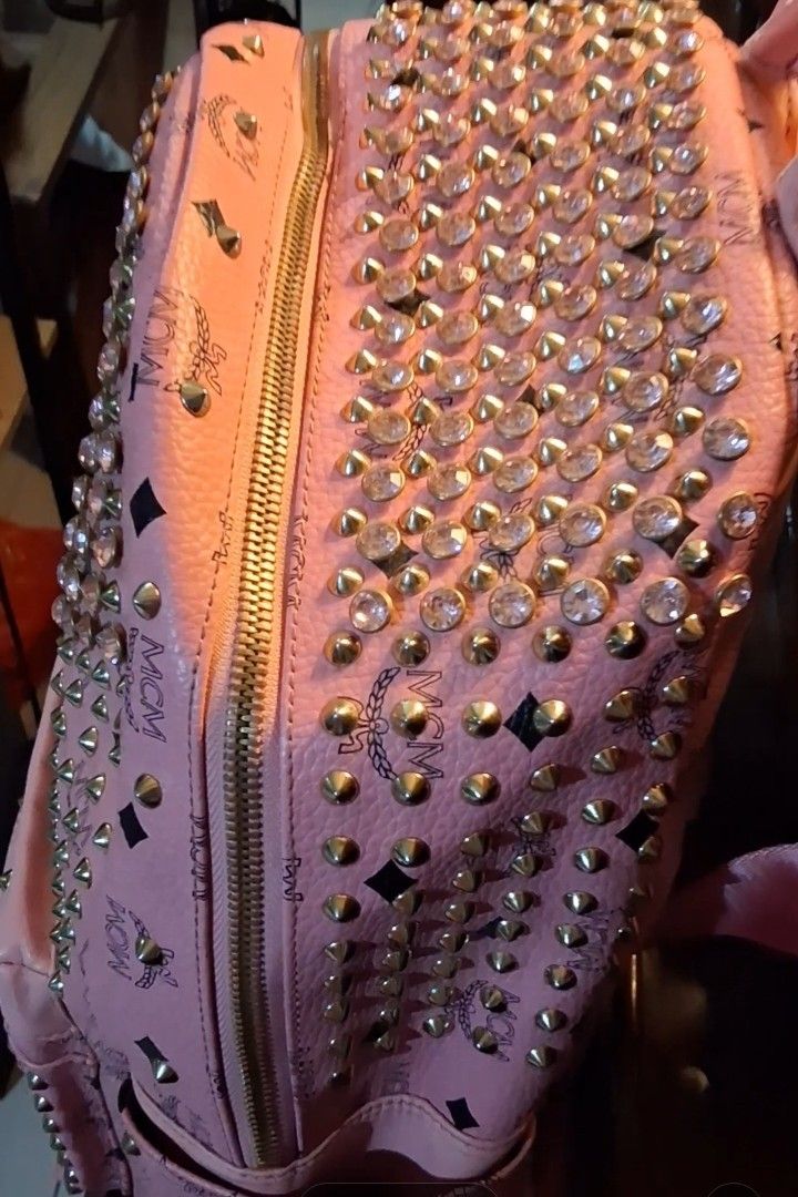 MCM Pink Studded Backpack with Crystals (Category: Backpacks) located in Taguig. Submitted by divine_kitty (Listing ID 1460917381, Image 2). Description: -Authemtic MCM STARCK MCM BACKPACK -SPECIAL EDITION Made in Korea - Eye-catching pink MCM backpack - Adorned with shimmering gold studs and clear crystals - Features the classic MCM logo pattern throughout - Secure zipper closure with a convenient front pocket - Adjustable straps for a comfortab