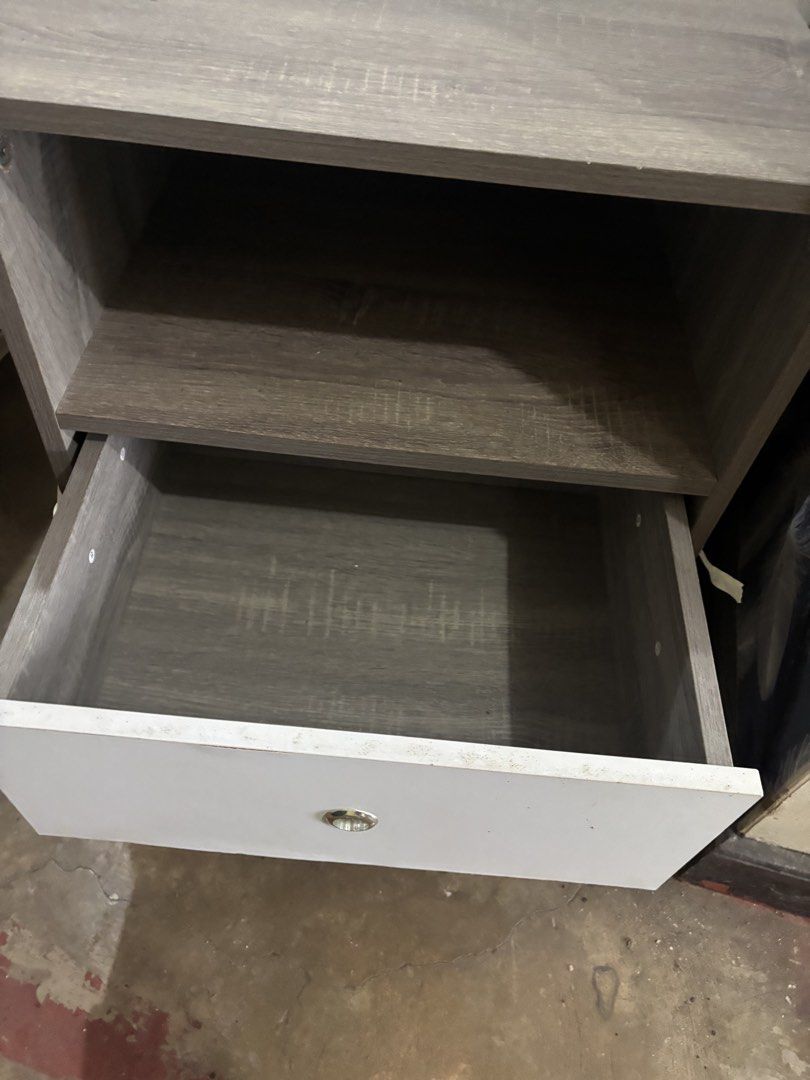 Modern Nightstand with Drawer and Open Shelf (Category: Shelves, Cabinets & Racks) located in Las Pinas. Submitted by whoshotcupid (Listing ID 1460891576, Image 2). Description: - Modern nightstand with grey wood grain finish on top and sides. - Features a clean white drawer front with a sleek silver knob. - Includes a convenient open shelf above the drawer for storage. - Supported by thin, durable black metal legs. - Versatile design suitable fo