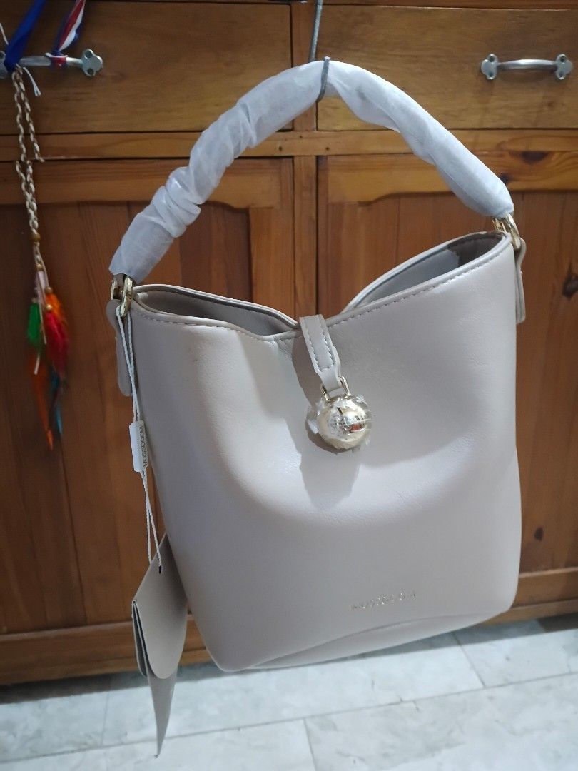Mossdoom Beige Bucket Bag with Gold Hardware (Category: Shoulder Bags) located in Cavite. Submitted by ms.de.clutter (Listing ID 1460790409, Image 1). Description: - Brand: Mossdoom - Style: Bucket Bag - Color: Beige - Accents: Gold - Includes: Original dust bag and tags - Condition: New (handle still has protective plastic wrap) - Interior: Zippered pocket and slip pocket - Exterior: Protective studs on the bottom.