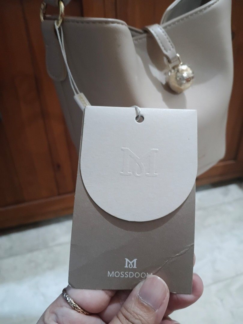 Mossdoom Beige Bucket Bag with Gold Hardware (Category: Shoulder Bags) located in Cavite. Submitted by ms.de.clutter (Listing ID 1460790409, Image 3). Description: - Brand: Mossdoom - Style: Bucket Bag - Color: Beige - Accents: Gold - Includes: Original dust bag and tags - Condition: New (handle still has protective plastic wrap) - Interior: Zippered pocket and slip pocket - Exterior: Protective studs on the bottom.