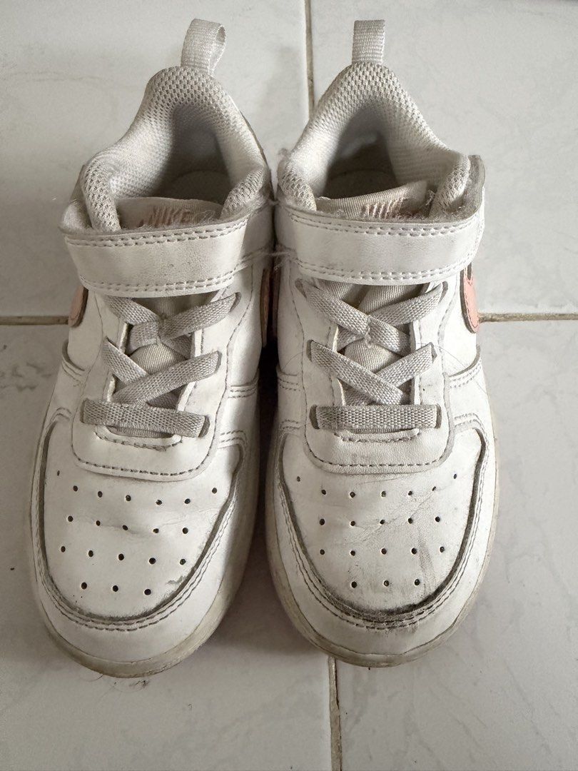 Nike Kids White Sneakers 9C (Category: Babies & Kids Fashion) located in Las Pinas. Submitted by bernalacosta (Listing ID 1460808671, Image 1). Description: - White Nike sneakers with pink accents - Features both Velcro strap and laces for a secure fit - Perforated toe box for breathability - Shows some signs of wear, particularly on soles and toe area - Still has plenty of life left for everyday use.