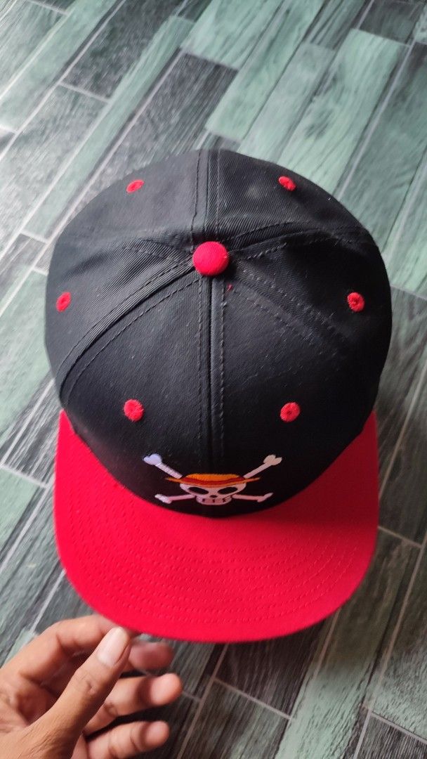 One Piece Straw Hat Pirates Snapback Cap (Category: Caps & Hats) located in Manila. Submitted by janyvony_315 (Listing ID 1460907234, Image 2). Description: - Black snapback cap with a striking red brim. - Features the iconic One Piece Straw Hat Pirates Jolly Roger logo embroidered on the front. - Red button on top and red eyelets for added detail. - Perfect for any dedicated One Piece fan! - Adjustable strap at the back for a comfortable, custom