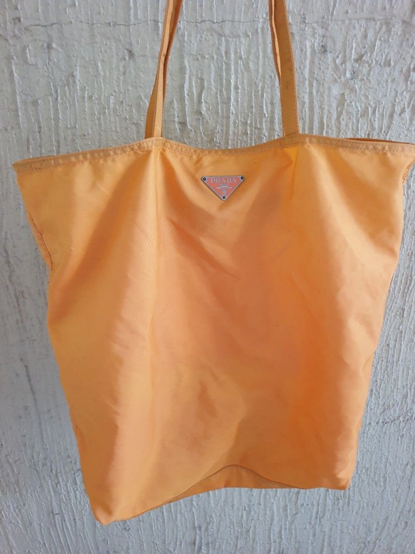 Prada Orange Nylon Tote Bag with Robot Applique (Category: Luxury Bags & Wallets) located in Las Pinas. Submitted by anggesmart (Listing ID 1460871222, Image 2). Description: - Authentic Prada orange nylon tote bag - Unique robot applique with mixed materials and stitching - Interior zippered pocket for secure storage - Crafted in Italy - Ideal for everyday wear or as a fashion statement -With minimal signs of usage, needs cleaning.