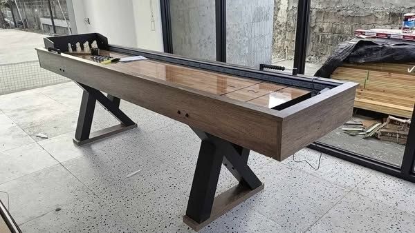 SHUFFLEBOARD TABLE (Category: Billiards and Bowling) located in San Pablo. Submitted by ablpsports (Listing ID 1460745529, Image 3). Description: - 2-in-1 Wooden Shuffleboard & Bowling Table - Includes 10 wooden pins, 4 pucks, and a brush - Smooth wooden playing surface - Sturdy wooden frame with black metal legs - Approximately 7-8 feet long - Ideal for family fun and game nights - Ready for pickup.