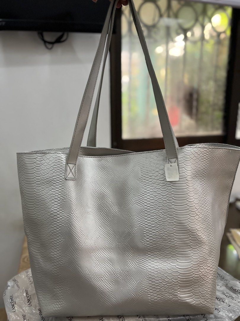 Silver Textured Tote Bag with Pouch (Category: Tote Bags) located in Quezon City. Submitted by happyshop31 (Listing ID 1460726728, Image 1). Description: - Chic silver tote bag - Unique snakeskin-like texture - Spacious interior - Comes with a navy blue inner pouch - Light grey handles - Ideal for everyday errands or travel - Unbranded.