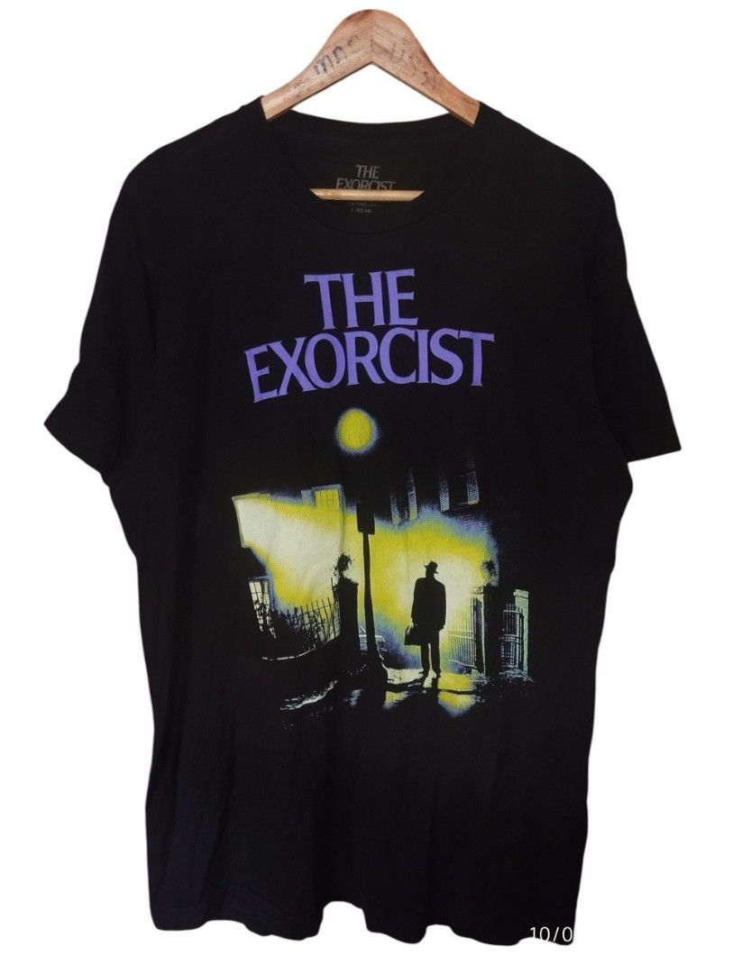 The Exorcist Black T-Shirt (Category: Tshirts & Polo Shirts ) located in Manila. Submitted by thriftjepo01336 (Listing ID 1460797617, Image 1). Description: - Black t-shirt featuring iconic 'The Exorcist' movie poster graphic. - Graphic shows a silhouette walking down a street at night with yellow light. - 'The Exorcist' title printed in purple text above the graphic. - Size: Large.