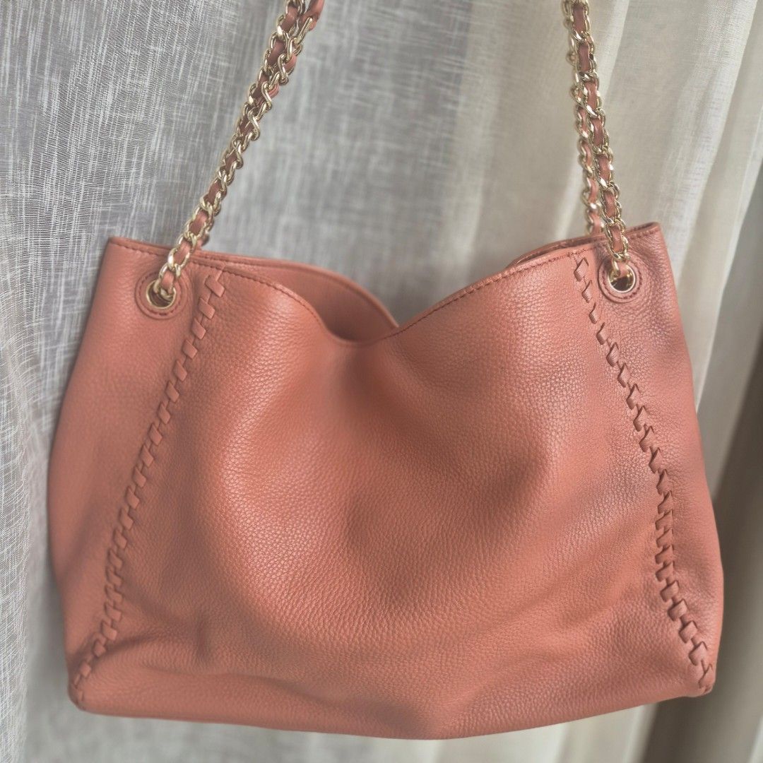 Tory Burch Leather Tote Bag with Chain Strap (Category: Luxury Bags & Wallets) located in Quezon City. Submitted by prelovedluxury21 (Listing ID 1460765741, Image 3). Description: - Salmon pink leather Tory Burch tote bag - Features braided stitch detail along edges - Gold chain strap - Iconic Tory Burch logo embossed on front - Spacious interior, perfect for everyday use - Shows some signs of wear on leather and hardware.