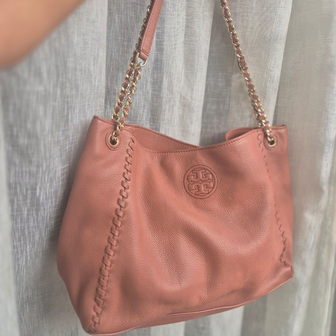 Tory Burch Leather Tote Bag with Chain Strap (Category: Luxury Bags & Wallets) located in Quezon City. Submitted by prelovedluxury21 (Listing ID 1460765741, Image 1). Description: - Salmon pink leather Tory Burch tote bag - Features braided stitch detail along edges - Gold chain strap - Iconic Tory Burch logo embossed on front - Spacious interior, perfect for everyday use - Shows some signs of wear on leather and hardware.