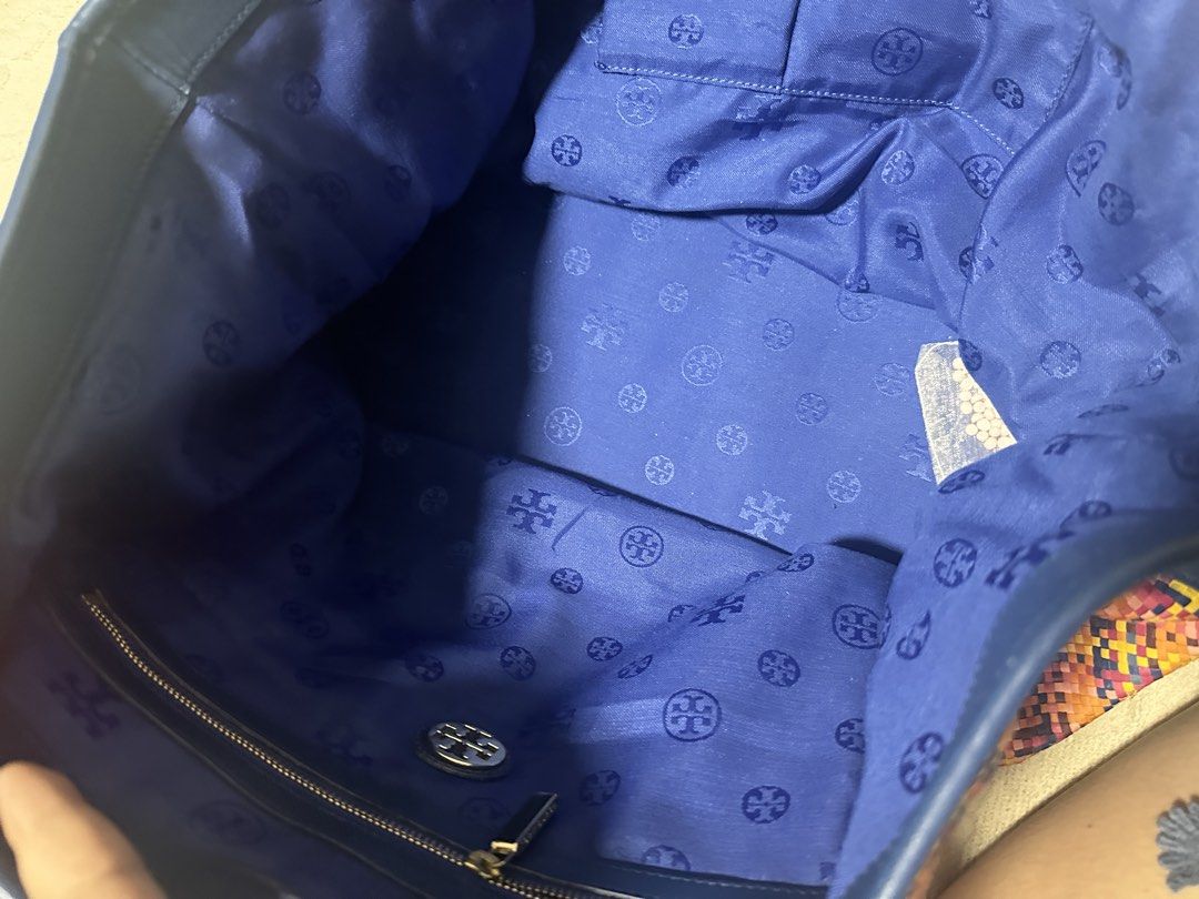 Tory Burch Woven Tote Bag (Category: Luxury Bags & Wallets) located in Makati City. Submitted by travel.pasabuy (Listing ID 1460841718, Image 3). Description: - Colorful woven tote bag - Navy blue leather handles and trim - Navy blue fabric lining with Tory Burch logo pattern - Interior zippered pocket - Spacious and stylish - Ideal for everyday use or beach trips.