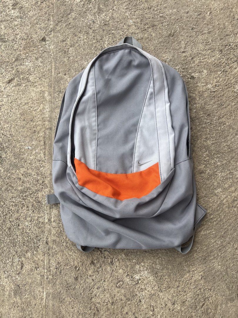 Vintage Nike Bag (Category: Backpacks) located in Manila. Submitted by thrifttolive (Listing ID 1460752806, Image 2). Description: - Grey Nike backpack with a vibrant orange accent. - Features adjustable straps for a comfortable fit. - Offers ample interior space, perfect for school or everyday essentials. - Shows some signs of wear, but remains fully functional..