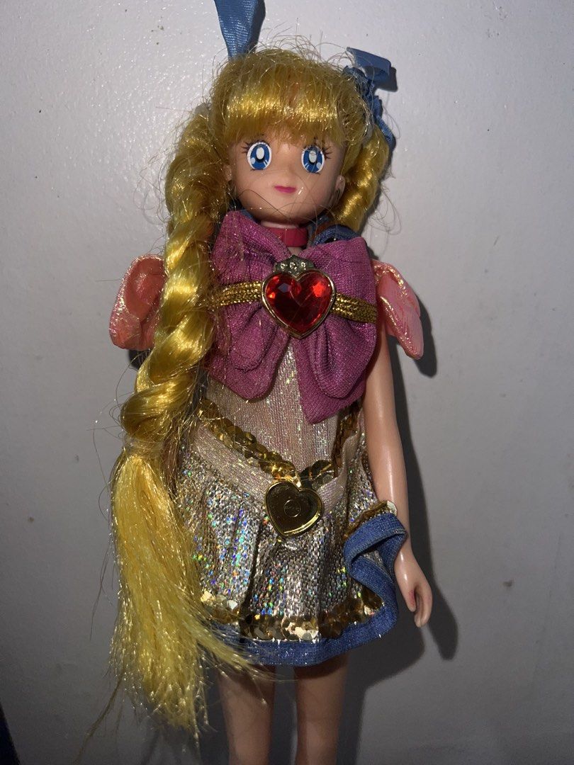 Vintage Sailor Moon Doll (Category: Plushies & Soft Toys) located in Manila. Submitted by asa68984 (Listing ID 1460874438, Image 2). Description: -Vintage Sailor Moon doll - Features long blonde pigtails and bright blue eyes - Wears a sparkly silver dress with a pink bow and red heart gem - Has delicate pink wings on her back - Ideal for doll collectors and imaginative play.