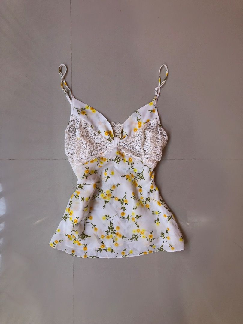 White Floral Cami Top with Lace Trim (Category: Sleeveless) located in Davao. Submitted by christ07_fox (Listing ID 1460862821, Image 1). Description: - White cami top - Yellow floral print - Delicate lace detailing along the bust - Adjustable spaghetti straps - Lightweight and flowy material - Perfect for layering or wearing solo.