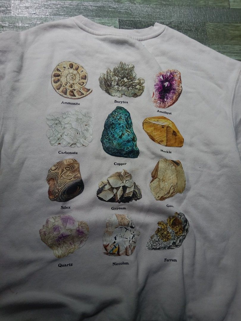 White Graphic Sweatshirt with Mineral Print (Category: Coats, Jackets and Outerwear) located in Manila. Submitted by chieezz (Listing ID 1460860051, Image 2). Description: - White crewneck sweatshirt - Features a graphic print on the back with various minerals (Quartz, Gypsum, Amethyst) - Text on the front: 'The Future Is Written In Stones Created of Manuscripts' - Comfortable and unique design - Ideal for casual wear.