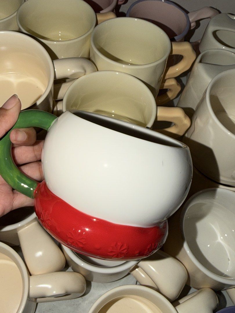 White mug with green handle and red snowflake base (Category: Coffee & Tea Tableware) located in Quezon City. Submitted by khensant0ss (Listing ID 1460815338, Image 1). Description: Cute white mug with a bright green handle. The base is red with a snowflake pattern. Perfect for hot drinks. Great for gifting or personal use. Stackable design for easy storage..