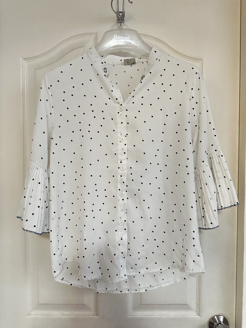 White Polka Dot Blouse with Pleated Bell Sleeves (Category: Blouses) located in Manila. Submitted by nfcloset_ (Listing ID 1460792567, Image 1). Description: - Classic white blouse with timeless black polka dots. - Elegant mandarin collar and convenient button-up front. - Unique bell sleeves add a touch of flair. - Pleated cuffs with a sophisticated dark trim. - Effortlessly transitions from casual to formal wear. - Perfect for a variety of occas