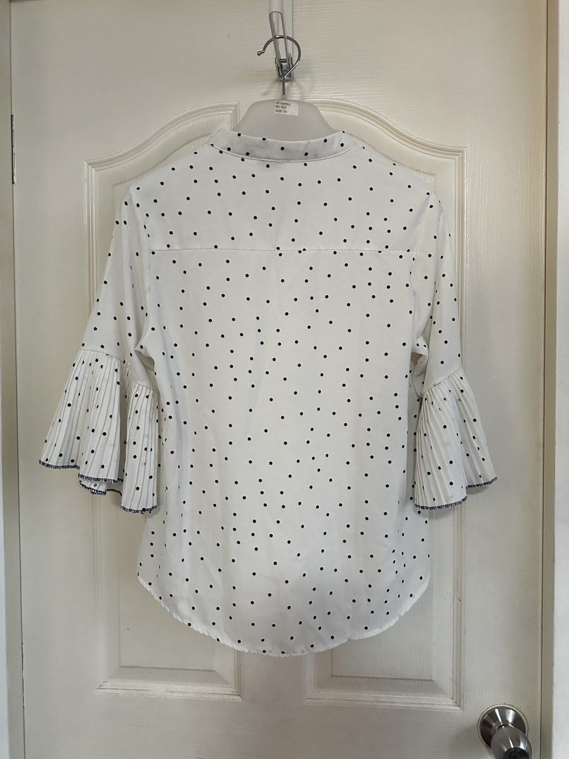 White Polka Dot Blouse with Pleated Bell Sleeves (Category: Blouses) located in Manila. Submitted by nfcloset_ (Listing ID 1460792567, Image 2). Description: - Classic white blouse with timeless black polka dots. - Elegant mandarin collar and convenient button-up front. - Unique bell sleeves add a touch of flair. - Pleated cuffs with a sophisticated dark trim. - Effortlessly transitions from casual to formal wear. - Perfect for a variety of occas