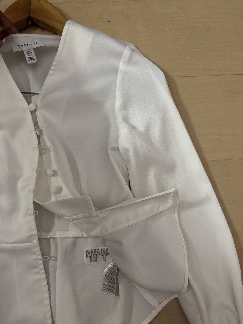 Authentic Topshop white longsleeve (Category: Blouses) located in Manila. Submitted by juhjuh (Listing ID 1460935457, Image 2). Description: - Topshop white peplum blouse - Made n Bangladesh - V-neck with button-up front - Long sleeves with buttoned cuffs - Fabric has a slight sheen - Estimated size: UK 8 - Perfect for dressing up or down.