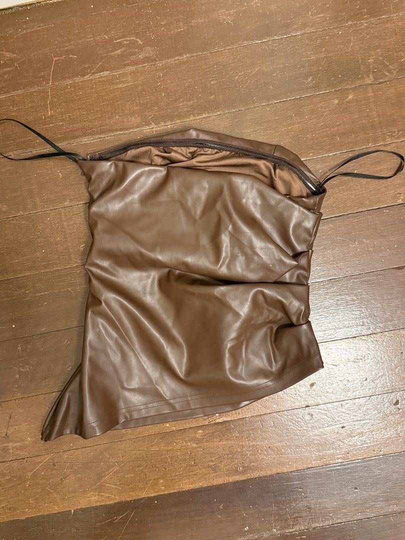 Brown Ruched Faux Leather Strapless Top (Category: Sleeveless) located in Angeles City. Submitted by lesmiz24601 (Listing ID 1460976056, Image 1). Description: - Brown strapless top - Ruched detailing - Faux leather material - Side zipper closure - Thin black straps - Estimated size: Small to Medium - Ideal for night outs or parties - Versatile: pair with jeans or a skirt.