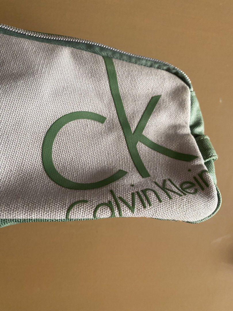 Calvin Klein CK Pouch Bag Green Grey (Category: Purses & Pouches) located in Baguio. Submitted by arenzu (Listing ID 1460949826, Image 2). Description: - Authentic Calvin Klein pouch - Color: Grey and Green - Features iconic CK logo print on the front - Secure zipper closure - Green fabric bottom - Interior has a small velcro pocket - Ideal for storing makeup, toiletries, or other small essentials.