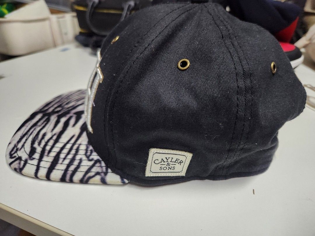 Cayler & Sons "RICH" Snapback Cap Zebra Print Undervisor (Category: Caps & Hats) located in Quezon City. Submitted by amber___18 (Listing ID 1460986709, Image 3). Description: - Brand: Cayler & Sons - Color: Black - Front Embroidery: "RICH" in white and gold - Underside of Brim: Zebra print - Back Embroidery: "Gates Trump LeBron" - Closure: Adjustable snapback.