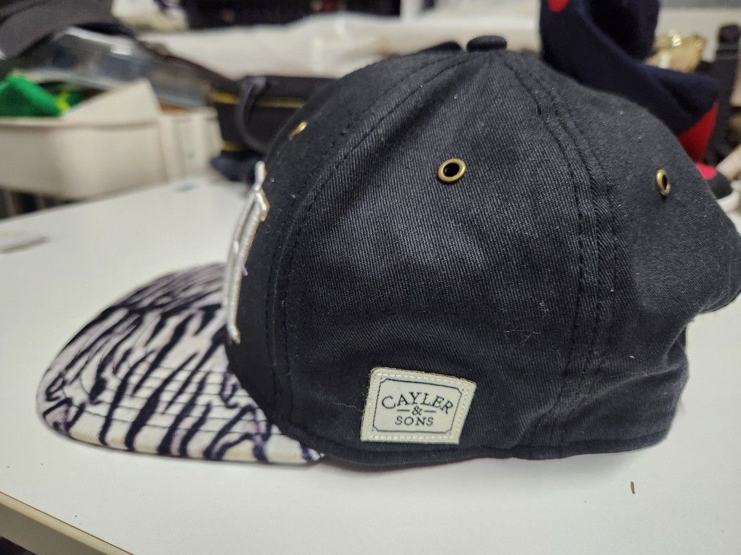 Cayler & Sons "RICH" Snapback Cap Zebra Print Undervisor (Category: Caps & Hats) located in Quezon City. Submitted by amber___18 (Listing ID 1460986709, Image 2). Description: - Brand: Cayler & Sons - Color: Black - Front Embroidery: "RICH" in white and gold - Underside of Brim: Zebra print - Back Embroidery: "Gates Trump LeBron" - Closure: Adjustable snapback.
