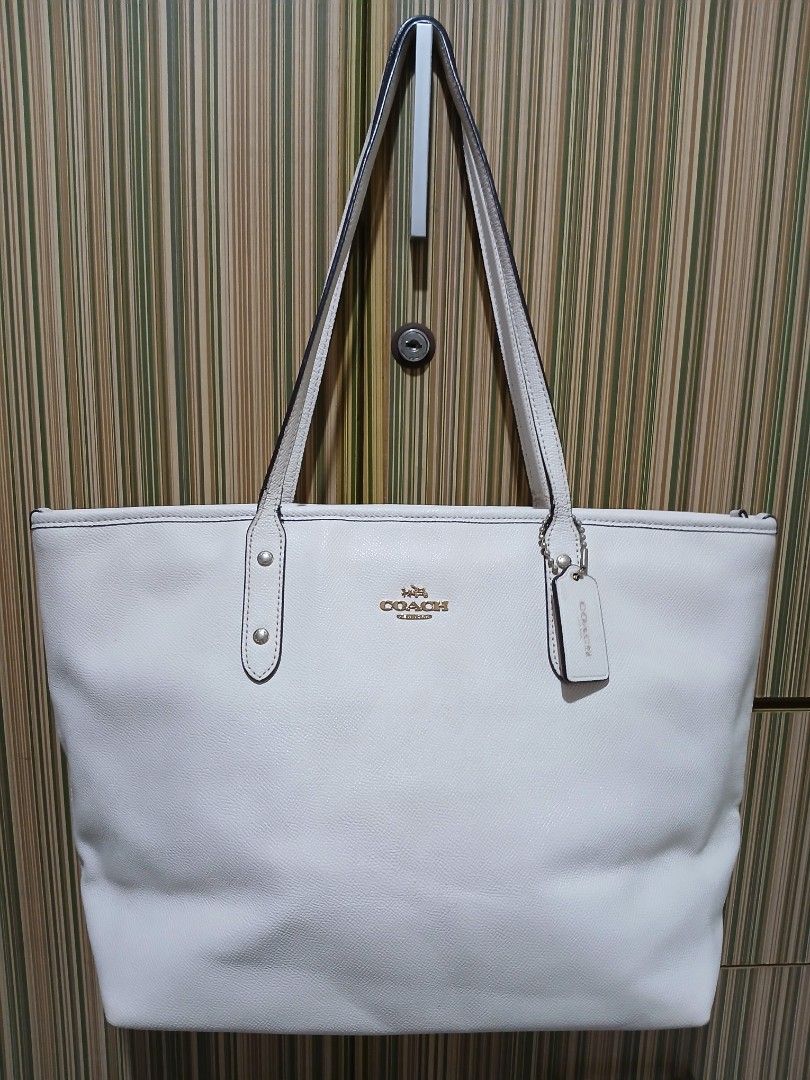 Coach White Leather Tote Bag (Category: Luxury Bags & Wallets) located in Taguig. Submitted by demsclosetph (Listing ID 1461005240, Image 1). Description: - Coach white leather tote bag - Elegant gold hardware details - Secure top zip closure - Roomy interior for all your essentials - Comfortable shoulder straps for easy carrying - Versatile for everyday use or travel - Timeless and classic design.