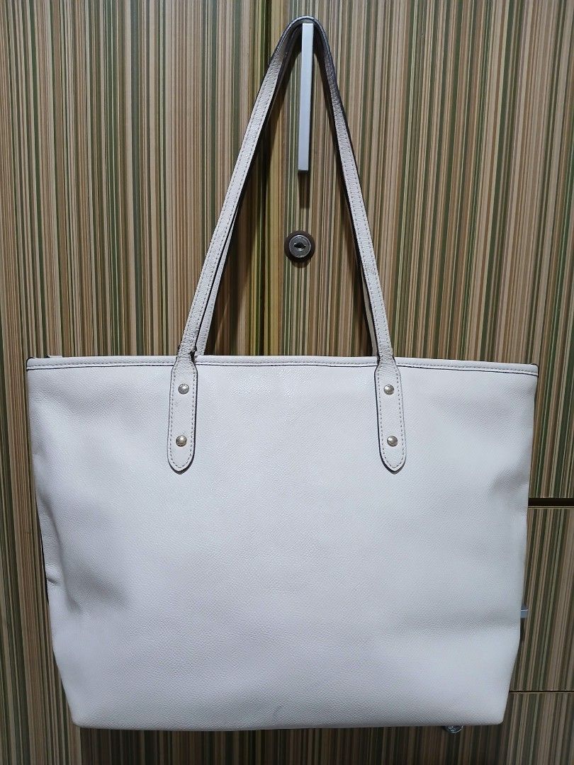 Coach White Leather Tote Bag (Category: Luxury Bags & Wallets) located in Taguig. Submitted by demsclosetph (Listing ID 1461005240, Image 2). Description: - Coach white leather tote bag - Elegant gold hardware details - Secure top zip closure - Roomy interior for all your essentials - Comfortable shoulder straps for easy carrying - Versatile for everyday use or travel - Timeless and classic design.