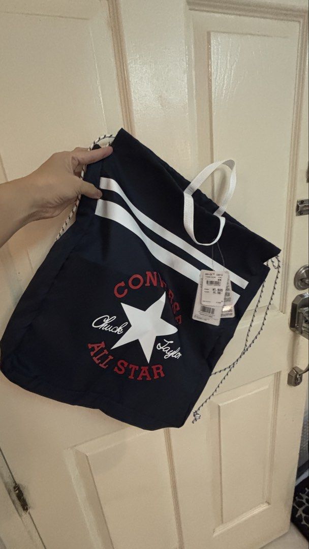 Converse Chuck Taylor All Star Navy Drawstring Bag (Category: Backpacks) located in Manila. Submitted by mamajho08 (Listing ID 1461029366, Image 2). Description: - Navy blue Converse drawstring bag - Features classic Chuck Taylor All Star logo (red & white) - Two white stripes across the front - Secure drawstring closure - Convenient white top handles - Brand new with original tags attached - Ideal for gym sessions or everyday errands.