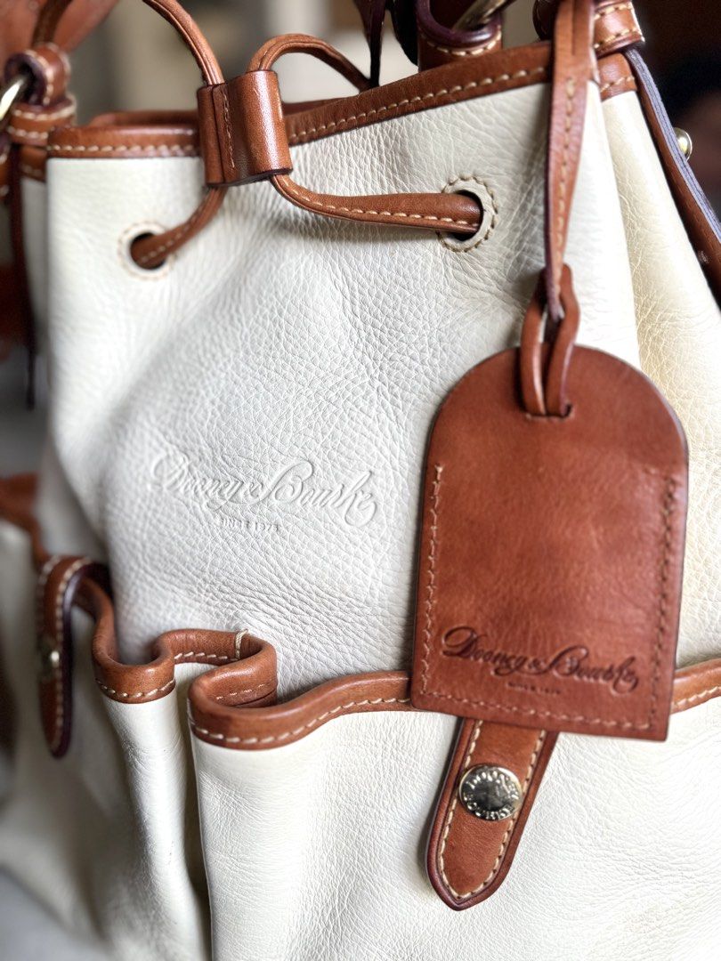 Cream Leather Drawstring Bucket Bag (Category: Luxury Bags & Wallets) located in Bacolod City. Submitted by vintage_vogue6100 (Listing ID 1461072206, Image 3). Description: - Cream leather bucket bag - Brown leather trim - Secure drawstring closure with tassels - Convenient exterior pockets with snap closures - Adjustable shoulder strap for comfortable carrying - Classic and timeless Dooney & Bourke design - Ideal everyday bag for all your essent