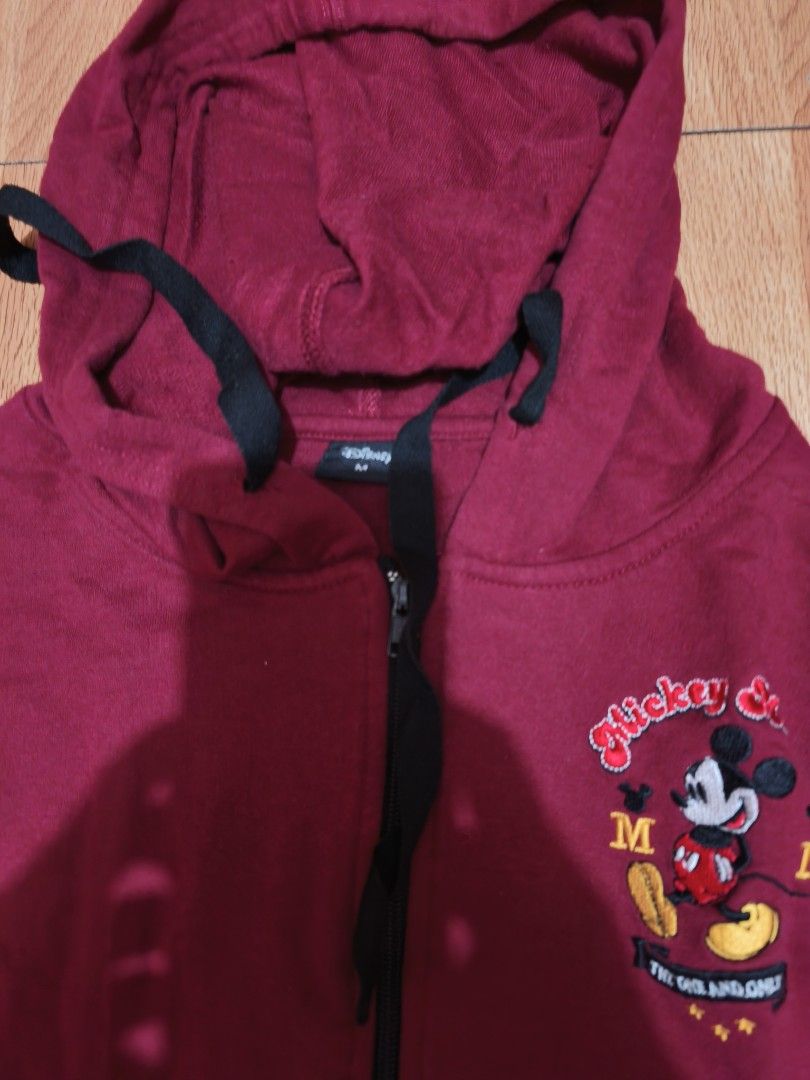 Disney Mickey Mouse Zip-Up Hoodie (Category: Hoodies) located in Quezon City. Submitted by acxsty (Listing ID 1461009749, Image 2). Description: - Maroon zip-up hoodie - Features a fun Mickey Mouse graphic on the front - 'Mickey Mouse' text detail on the sleeve - Adjustable drawstring hood - Two convenient front pockets - Ideal for everyday casual wear.