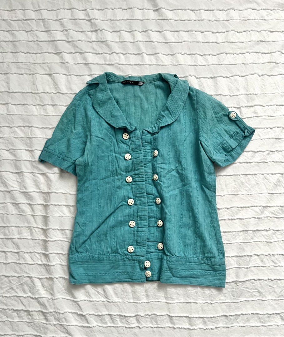 Express Teal Double-Breasted Short Sleeve Blouse (Category: Blouses) located in Makati City. Submitted by lovedbyliv_ (Listing ID 1461027735, Image 1). Description: - vintage teal blue top - Double-breasted button-up front with white buttons - Subtle vertical stripe texture - Cute Peter Pan collar - Button accents on sleeves - Perfect for casual or semi-formal occasions.