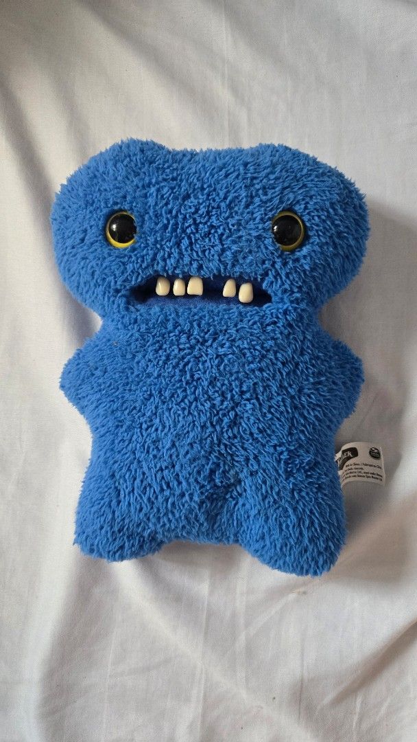 FUGGLER - Blue Gaptooth Mcgoo (Category: Plushies & Soft Toys) located in Manila. Submitted by fierceriver.e57033 (Listing ID 1460953334, Image 1). Description: - No box, with pen marks on tag. - Adorable blue plush toy, approximately 9 inches in length. - Features big, fun googly eyes and a row of cute teeth. - Made from super soft and fuzzy material for a cuddly feel. - Includes a small button detail on the back. - Ideal for children's playtime