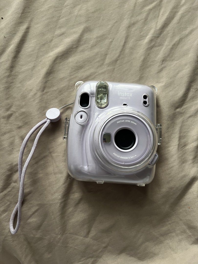 Fujifilm Instax Mini 11 Lavender Instant Camera (Category: Cameras) located in Valenzuela. Submitted by decluttering.manila (Listing ID 1461002943, Image 1). Description: - Lavender Fujifilm Instax Mini 11 camera - Comes with a clear protective case - Includes a wrist strap - 60mm lens with focus range from 0.3m to infinity - Ideal for capturing instant memories - Fully functional and works well.